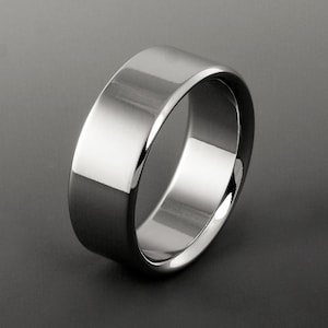 May include: A polished silver-toned metal ring with a smooth, flat outer surface and a wide band design. The ring features a reflective, high-shine finish that catches the light, creating distinct highlights along the curved edges of the band.