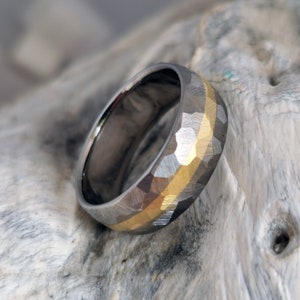 May include: A hammered silver and gold wedding band with a textured finish.