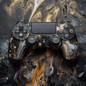 May include: Black PlayStation 4 controller with a custom marbled design in gold, white, and black. The controller features the standard button layout and a PlayStation logo. The background is a matching abstract pattern.