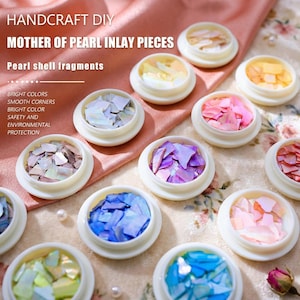 Puede incluir: Pequeños recipientes blancos llenos de piezas de incrustación de nácar de colores. La imagen incluye el texto "HANDCRAFT DIY MOTHER OF PEARL INLAY PIECES" y "Pearl shell fragments". Las piezas de incrustación son de varios colores, como rosa, azul y morado.