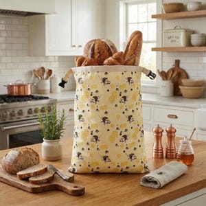 May include: A white ceramic mug with a black handle and the text "But First, Coffee" in a black, handwritten-style font. The mug is on a white surface.