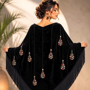 Luxury black velvet shawl with colorful jeweled embellishments and long black fringe, worn by an elegant woman in a professional studio setting, back view showcasing detailed handcrafted design.