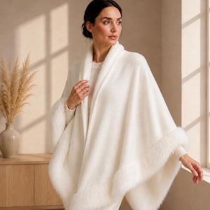 Peut inclure: Un poncho en tricot de couleur crème doté d'un large col châle et d'une bordure épaisse en fausse fourrure le long de l'ourlet. Le vêtement est porté sur un pull à manches longues et un pantalon large assortis, créant un ensemble monochrome.