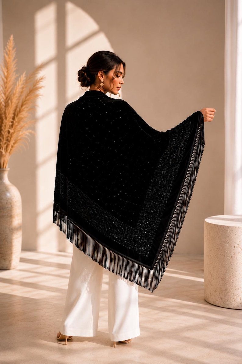 Luxury black velvet formal wrap draped over the shoulders, showcasing sparkling crystal accents, triangular silhouette and handcrafted fringe trim.