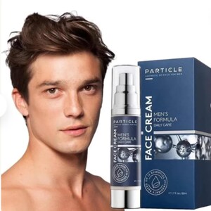 K&ouml;nnte beinhalten: Ein Mann steht neben einer Flasche Particle Men's Formula Face Cream und einer Schachtel desselben Produkts. Flasche und Schachtel sind dunkelblau mit wei&szlig;em Text. Die Flasche ist 50 ml.