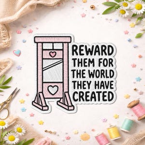 May include: A pink embroidered patch featuring a guillotine design with heart details. The patch includes the text "REWARD THEM FOR THE WORLD THEY HAVE CREATED" in black. The patch is surrounded by sewing supplies and floral accents.