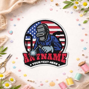 May include: Embroidered patch featuring a welder in a blue uniform and a welding mask, set against an American flag design. The patch includes the text "ANYNAME" in red and "YOUR TEXT HERE" in white.