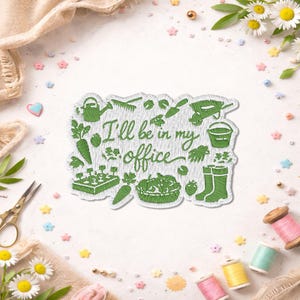 May include: Green embroidered patch with gardening tools and the text "I'll be in my office." The patch features a watering can, carrots, a trowel, a wheelbarrow, a bucket, and other gardening-related images. Daisies and sewing supplies surround the patch.