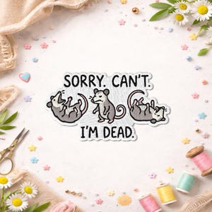 May include: An embroidered patch featuring three gray and white opossums in various poses with the black text SORRY. CAN'T. I'M DEAD. The opossums are depicted with pink noses, ears, and tails, arranged horizontally on a white fabric background.