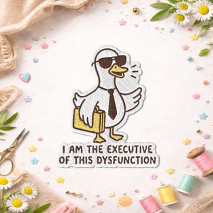 May include: Embroidered patch featuring a cartoon duck wearing sunglasses, a tie, and carrying a briefcase. The patch has the text "I AM THE EXECUTIVE OF THIS DYSFUNCTION". The patch is white, brown, and yellow.