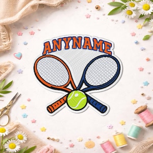 May include: An embroidered patch featuring two crossed tennis rackets, one orange and one blue, with a bright yellow tennis ball at the center. The word ANYNAME is stitched in orange letters with a blue outline in an arc above the rackets.
