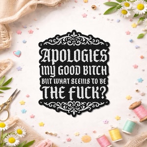May include: Black and white embroidered patch with the text "APOLOGIES my GOOD BITCH BUT WHAT SEEMS TO BE THE FUCK?". The patch has a decorative border and is surrounded by sewing supplies and flowers.