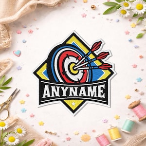 May include: A diamond-shaped embroidered patch featuring a target with three red-fletched arrows hitting the center. The design includes yellow, blue, and black borders with the white text ANYNAME centered on a black banner at the bottom.