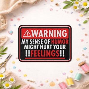 May include: A black and red embroidered patch with the text "WARNING MY SENSE OF HUMOR MIGHT HURT YOUR !!FEELINGS!!". The patch has a red border and a warning symbol at the top. The patch is surrounded by sewing supplies and decorative elements.