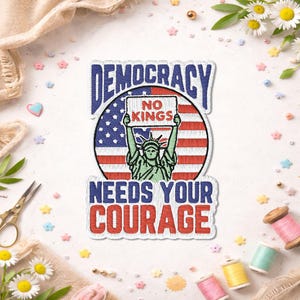 May include: Embroidered patch with the text "DEMOCRACY NEEDS YOUR COURAGE." The patch features the Statue of Liberty holding a sign that reads "NO KINGS" against a backdrop of the American flag. The patch is surrounded by a white border.