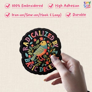 Peut inclure: &Eacute;cusson brod&eacute; avec un motif d'oiseau color&eacute; et l'inscription "RADICALIZED BY BASIC DECENCY" en cercle. L'&eacute;cusson noir a un bord festonn&eacute; et un oiseau aux teintes jaunes, bleues et oranges. Il peut &ecirc;tre appliqu&eacute; par repassage, couture ou velcro.