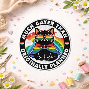 Peut inclure: Écusson brodé avec un chat noir portant des lunettes de soleil en forme de cœur arc-en-ciel et une cape arc-en-ciel. Le texte "MUCH GAYER THAN ORIGINALLY PLANNED" entoure le chat. L'écusson est rond avec une bordure noire.