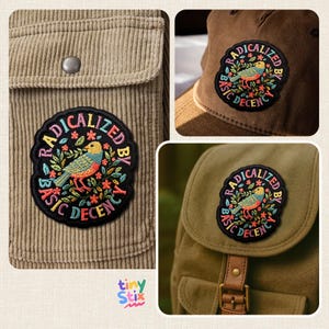 Peut inclure: &Eacute;cusson brod&eacute; avec un motif d'oiseau color&eacute; et le texte "RADICALIZED BY BASIC DECENCY" en cercle. L'&eacute;cusson est pr&eacute;sent&eacute; sur une veste en velours c&ocirc;tel&eacute;, une casquette de baseball et un sac &agrave; dos.
