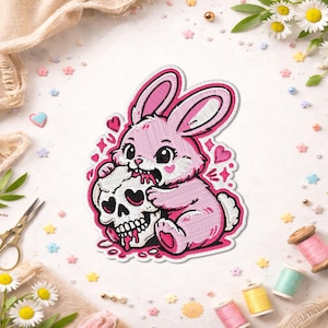 May include: A pink bunny patch with a skull, hearts, and a white outline. The bunny is biting the skull, with red dripping from the skull's mouth. The patch is surrounded by decorative elements.