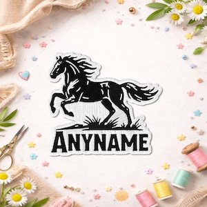 May include: An embroidered patch featuring a black horse in a prancing pose above the text ANYNAME in bold black capital letters. The patch has a white border and is designed to be applied to fabric surfaces for decorative personalisation purposes.