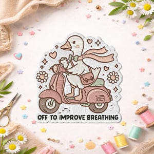 May include: Embroidered patch featuring a goose riding a pink scooter, wearing a scarf and carrying a bag. The patch has the text "OFF TO IMPROVE BREATHING" and is surrounded by decorative elements like hearts and flowers.