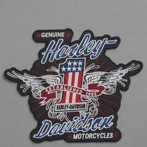 May include: A black Harley-Davidson patch with white wings and the text "Genuine Harley-Davidson Motorcycles." The patch features a red, white, and blue design with the text "Established 1903."