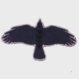 Puede incluir: Parche bordado con un cuervo negro en vuelo. Las alas del ave están extendidas y los bordes están delineados en color lila claro. Diseñado para coser en tela.