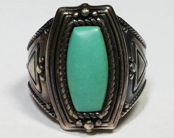 Puede incluir: Un anillo de plata con una piedra turquesa engastada en un diseño geométrico.
