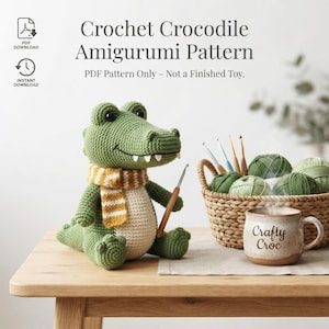 May include: A crochet crocodile amigurumi pattern PDF featuring a green stuffed crocodile with a cream belly and a yellow and white striped scarf, holding a crochet hook. Text reads: Crochet Crocodile Amigurumi Pattern. PDF Pattern Only.
