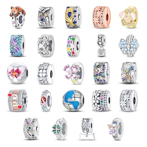 May include: A collection of twenty-four silver-toned metal charms for bracelets, featuring various designs including a red panda, butterflies, flowers, puzzle pieces, a globe, hearts, and colorful gemstones in diverse shapes and patterns.