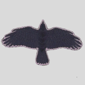 May include: A black embroidered patch in the shape of a crow with outstretched wings. The patch has a light purple border and is set against a light gray background. The crow's wings are fully extended.
