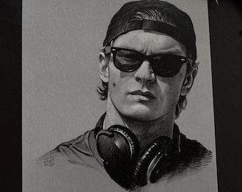 May include: A black and white graphite drawing on gray paper depicting a person wearing a baseball cap, dark sunglasses, and over-ear headphones around their neck. The portrait features detailed shading and the artist's signature M.29 W.26.