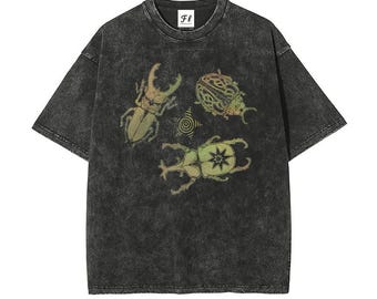 Puede incluir: Una camiseta gris carbón con efecto lavado al ácido que presenta un estampado gráfico de dos escarabajos y una pequeña estrella. La prenda tiene mangas cortas, cuello redondo y una etiqueta blanca con el texto FL PROJECT.