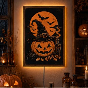 Puede incluir: Un cuadro rectangular con un fondo de luna naranja brillante, una calabaza tallada con un sombrero de bruja negro, murciélagos, una araña, dulces de maíz y una botella de cristal, enmarcado con retroiluminación LED cálida integrada.