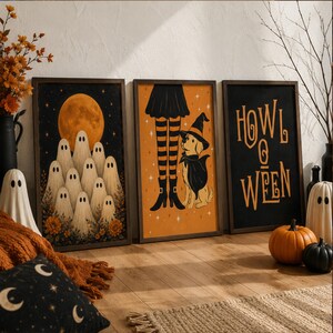 May include: Three framed rectangular wall art prints with Halloween themes. The left print shows ghosts under a large orange moon. The center print features a dog in a witch hat and cape next to striped stockings. The right print displays the text HOWL O WEEN.