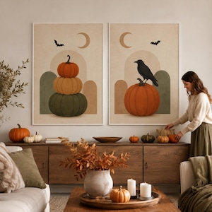 Puede incluir: Dos láminas decorativas rectangulares en marcos blancos. La lámina izquierda muestra una pila de tres calabazas en naranja, amarillo y verde con una luna creciente y un murciélago. La derecha presenta un cuervo negro sobre una calabaza.