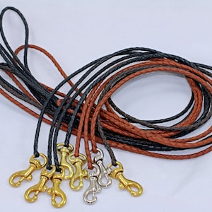 May include: A set of braided leather cords with gold and silver clasps. The cords are brown and black.