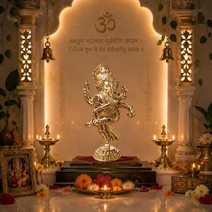 May include: A golden statue of the Hindu deity Ganesha in a decorative setting. The statue is on a wooden platform with a red cloth, surrounded by candles, flowers, and a framed picture. The background features an arch with Sanskrit text and the Om symbol.