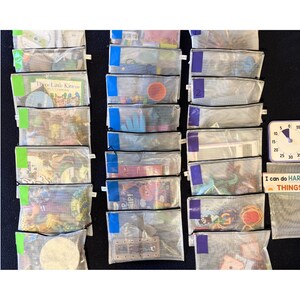 May include: A collection of clear mesh zipper pouches, each containing various small items. Some pouches have colored tape accents. A small clock and a sign that reads "I can do HARD THINGS" are also visible.