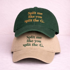 Peut inclure: Deux casquettes de baseball, une vert foncé et une beige, superposées. Les deux casquettes portent la phrase brodée "Split me like you split the G." dans une couleur contrastante.