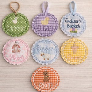May include: Embroidered Easter-themed gift tags with scalloped edges. Each tag features a different design, including a duck, bunny, lamb, cross, and dog. Names like "Cameron", "Olivia", "Hazel", "Parker", "Emma", "Reed", and "Jackson's Basket" are embroidered on the tags.
