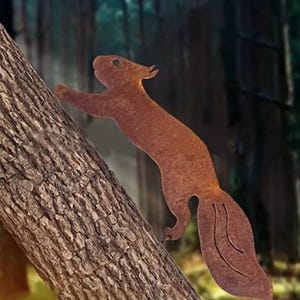 Puede incluir: Una escultura de metal de color marrón oxidado de una ardilla trepando por un árbol. La ardilla tiene una cola larga y tupida y está unida a un tronco de árbol texturizado. El fondo es una escena borrosa del bosque.