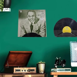 May include: Vintage vinyl record album cover featuring Ivory Joe Hunter, with the album title "I Had a Girl". The album cover is displayed on a green wall, along with a record player and other decorative items.