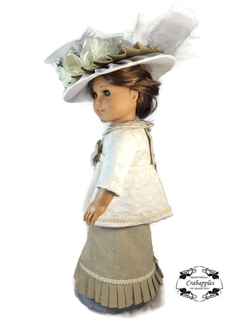 May include: A doll wearing a white jacket with a beige skirt and a white hat with a large white flower and a white feather. The doll is standing on a white background. The doll is wearing a white jacket with a beige skirt and a white hat with a large white flower and a white feather. The doll is standing on a white background.