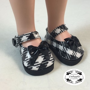 May include: Black and white houndstooth doll shoes with black bows and a black buckle. The shoes are made for dolls.