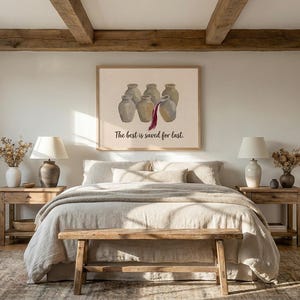 May include: A rectangular wall art print in a light wood frame featuring five beige ceramic jugs, with a dark red liquid pouring from the center jug into the one in front. The text below reads, The best is saved for last. The print is centered.
