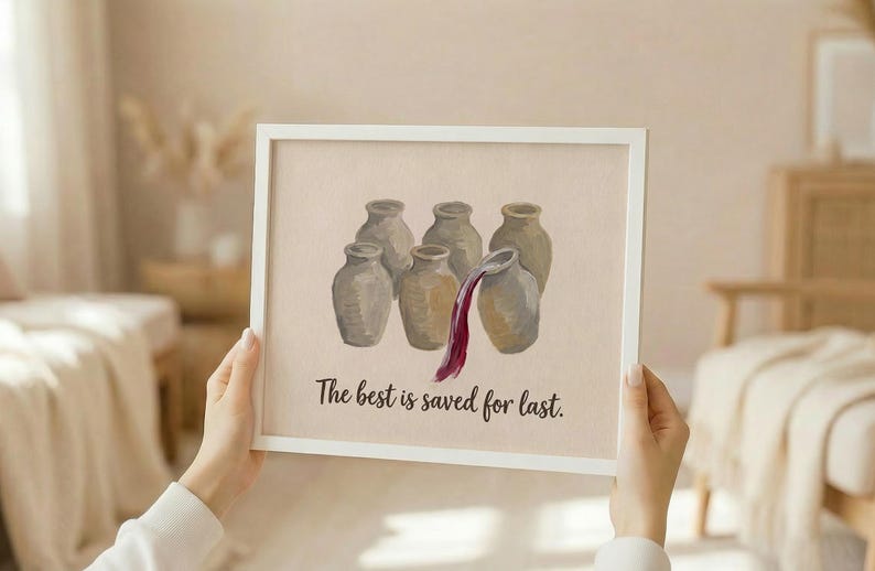 May include: A white framed wall art print featuring an illustration of six beige ceramic jars, with dark red liquid pouring from the rightmost jar. Below the jars, the text reads, The best is saved for last, in a dark brown cursive script.