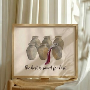 May include: A framed print featuring six light brown ceramic jars arranged in a group. One jar on the right is tilted, pouring out a stream of dark red liquid. Below the jars, the text reads, "The best is saved for last." in a dark font.