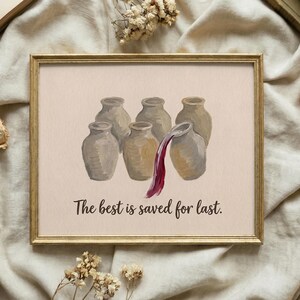 May include: A framed print featuring six beige ceramic jars arranged in a group. One jar on the right is tilted, pouring out a stream of deep red liquid. Below the jars, the text reads, "The best is saved for last." in a dark brown script font.