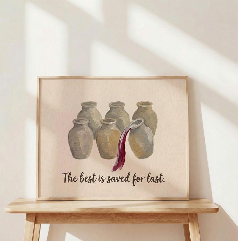 May include: A framed wall art print featuring six beige ceramic jars arranged in two rows. A stream of dark red liquid pours from the top right jar. The text "The best is saved for last." is printed in black script below the jars on a light background.